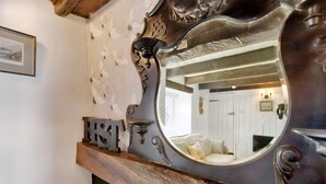 Ein Spiegel mit aufwendiger Metallverzierung, ein Kamin und eine weiße Wand mit einem gerahmten Bild.