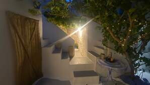 Een trap leidt naar een balkon met uitzicht op de lucht, een tafeltje met decoratieve objecten, en een boom met lichtjes.