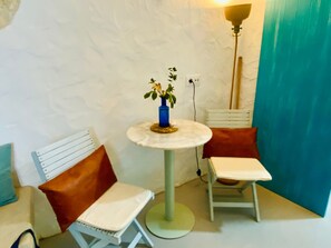 A small room with a white wall, a round table with a blue vase, two white chairs with brown cushions, and a tall floor lamp. - Cave apartment in the heart of the center (Vejer de la Frontera)