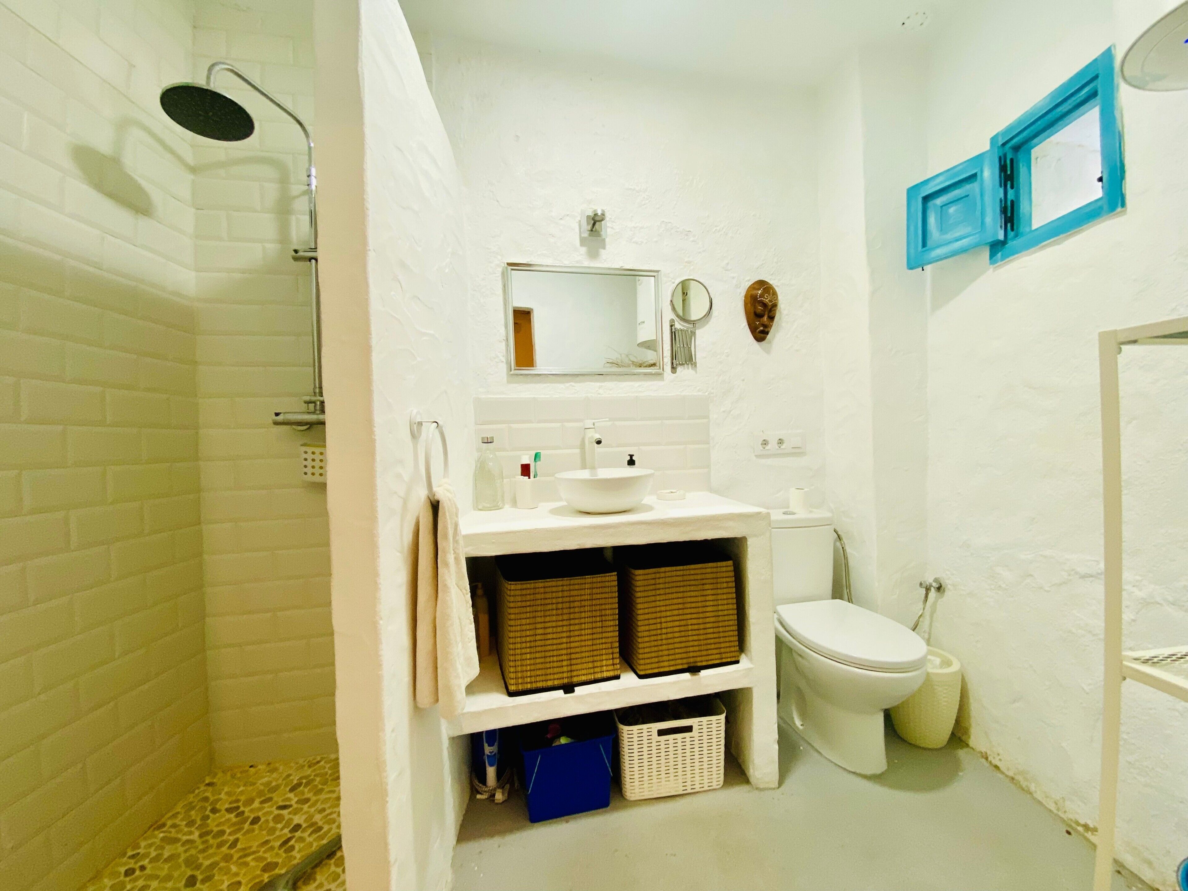 Een badkamer met douche, toilet, wastafel en spiegel.