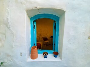 A window with a blue frame, a white wall, and a small shelf with a terracotta pot and two blue bowls. - Cave apartment in the heart of the center (Vejer de la Frontera)