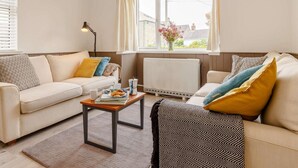 Uma sala de estar com sofá, mesa de centro e janela com cortinas.
