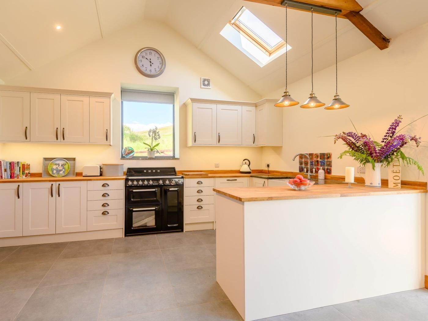 A kitchen with a central island, a stove, cabinets, and a skylight.