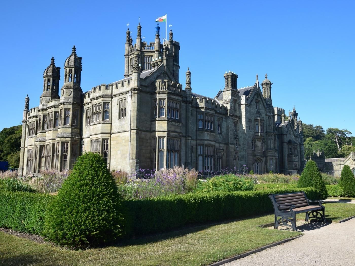 Un grand bâtiment historique doté de nombreuses tours et d’un jardin bien entretenu.
