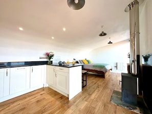 A compact kitchen with white cabinets, a central island, and a wood floor. - 1 Bed in Bude (oc-88497) (Morwenstow)