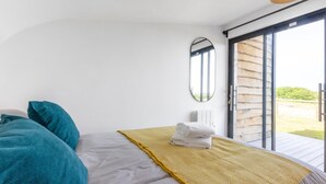 Ein Schlafzimmer mit einem Bett, einem Spiegel, einem Fenster und einer Tür, die zu einem Außenbereich führt.