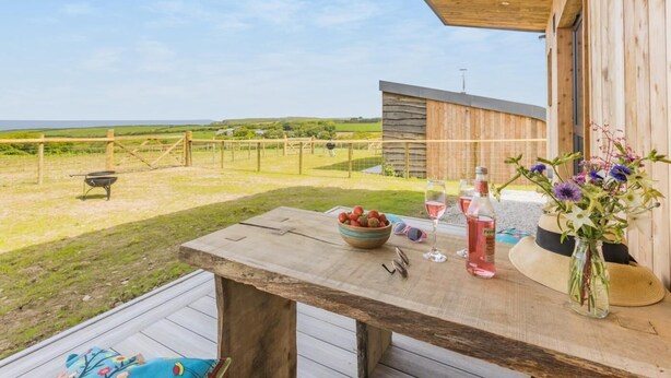 Eine Holzterrasse mit einem Tisch, einer Obstschüssel und einem Blumenstrauß.