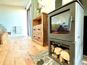 A room with a fireplace, wooden dresser, and a bed. - 1 Bed in Bude (oc-88497) (Morwenstow)