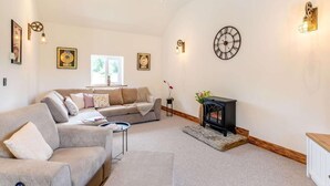 Un salón espacioso con sofá, chimenea y relojes en la pared.