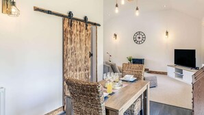 Una sala de estar moderna con comedor, televisor y un amplio ventanal corredero de madera.