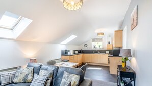 En moderne loftlejlighed med et opholdsområde med en lædersofa, et spisebord og et køkken med træskabe og et skydelugt.