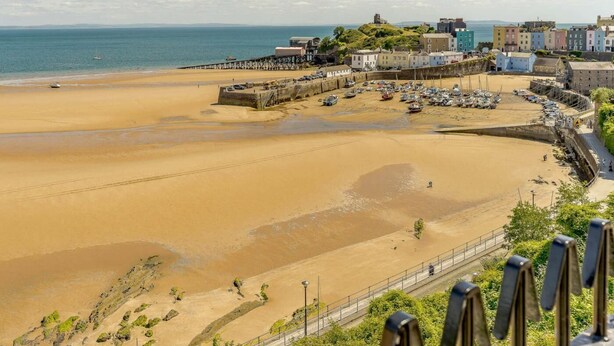 A coastal town with a sandy beach, a pier, and colorful buildings. - 2 Bed in Tenby (oc-88738) (Tenby)