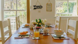 A breakfast table with plates, a glass of orange juice, and a clock on the wall. - 2 Bed in Tenby (oc-88738) (Tenby)
