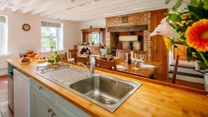 A kitchen with a wooden countertop, stainless steel sink, and a brick wall. - 4 Bed in Corwen (oc-88868) (Corwen)