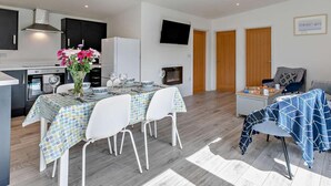 A modern kitchen with a dining area, a flat-screen TV, and a cozy seating area with a blanket. - 2 Bed in Camborne (oc-88826) (Camborne)