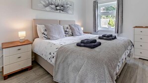A bedroom with a bed, bedside tables, a lamp, a window with curtains, and a wall-mounted artwork. - 2 Bed in Camborne (oc-88826) (Camborne)