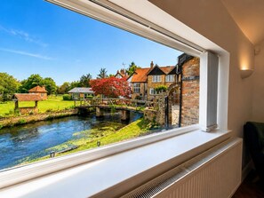 A view of a river with a bridge, stone buildings, and a lawn. - Luxury 5BDR Riverside Retreat near Uxbridge (Harefield)