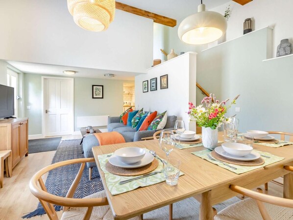 Una sala de estar moderna con comedor, muebles de madera y un ventanal grande.
