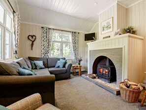 Ein gemütliches Wohnzimmer mit Kamin, einer Couch und einem gemusterten Vorhang.