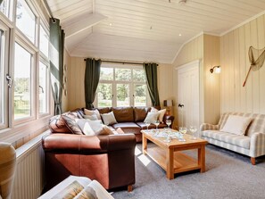 Ein gemütliches Wohnzimmer mit einem braunen Ledersofa, einem karierten Sofa und einem Couchtisch aus Holz mit Gläsern.