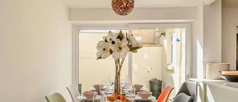 A dining table set with plates, bowls, glasses, and a vase of flowers.