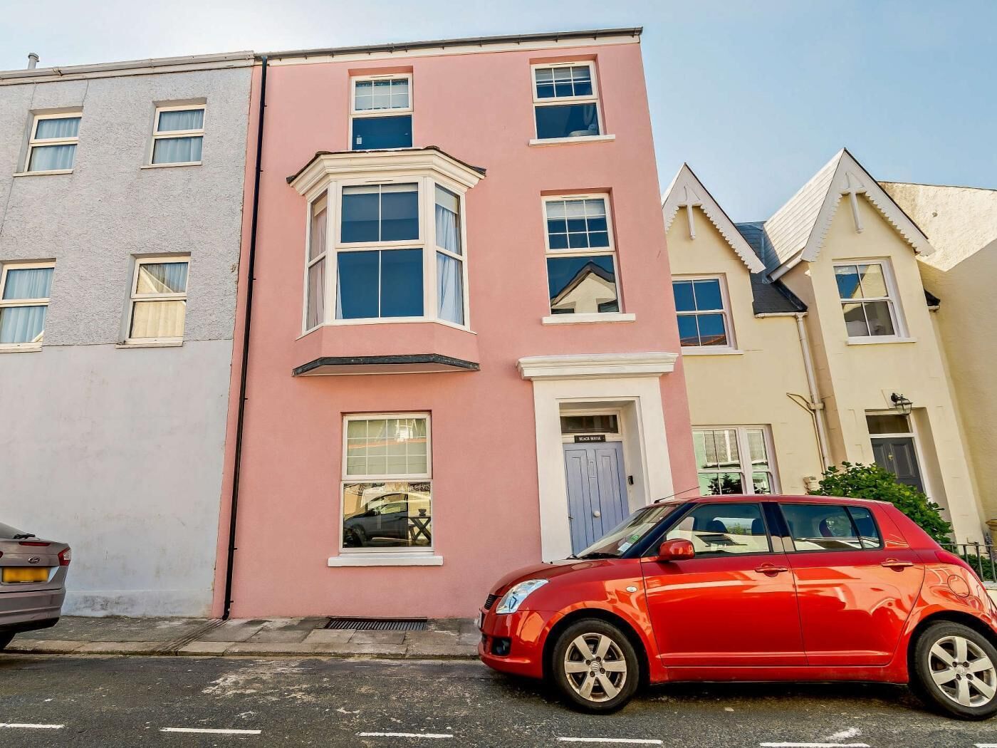 A row of terraced houses with a red car parked in front.