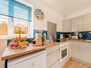 A kitchen with a wooden countertop, a kettle, a toaster, and a clock on the wall. - 2 Bed in Malmesbury (oc-89025) (Minety)