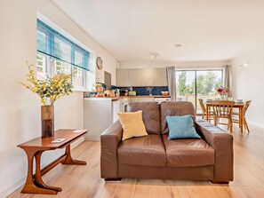 A modern living room with a brown leather sofa, a wooden coffee table, and a dining area with a wooden table and chairs. - 2 Bed in Malmesbury (oc-89025) (Minety)