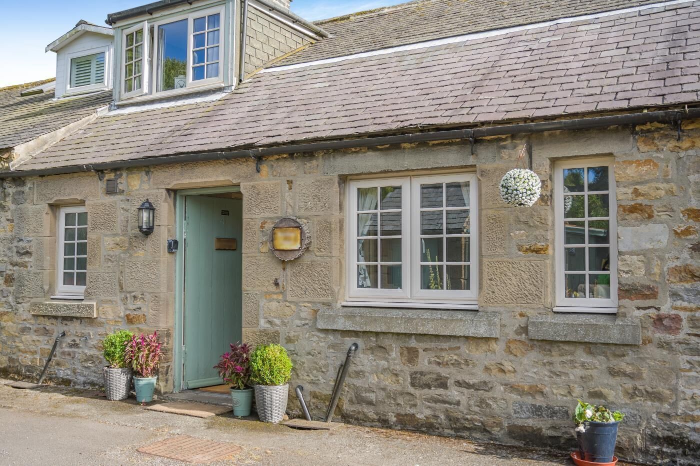 A stone building with a green door, multiple windows, and a small balcony.
