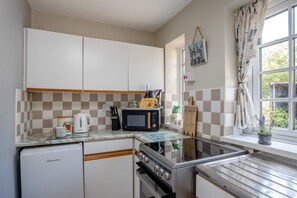 Eine kleine Küche mit Kühlschrank, Mikrowelle, Herd und Spüle.