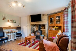 A cozy living room with a fireplace, a television mounted on the wall, and a dining area with a table and chairs. - 1 Bed in Hexham (oc-89085) (Bellingham)