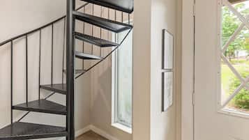 A black spiral staircase in a room with a window and framed pictures on the wall.