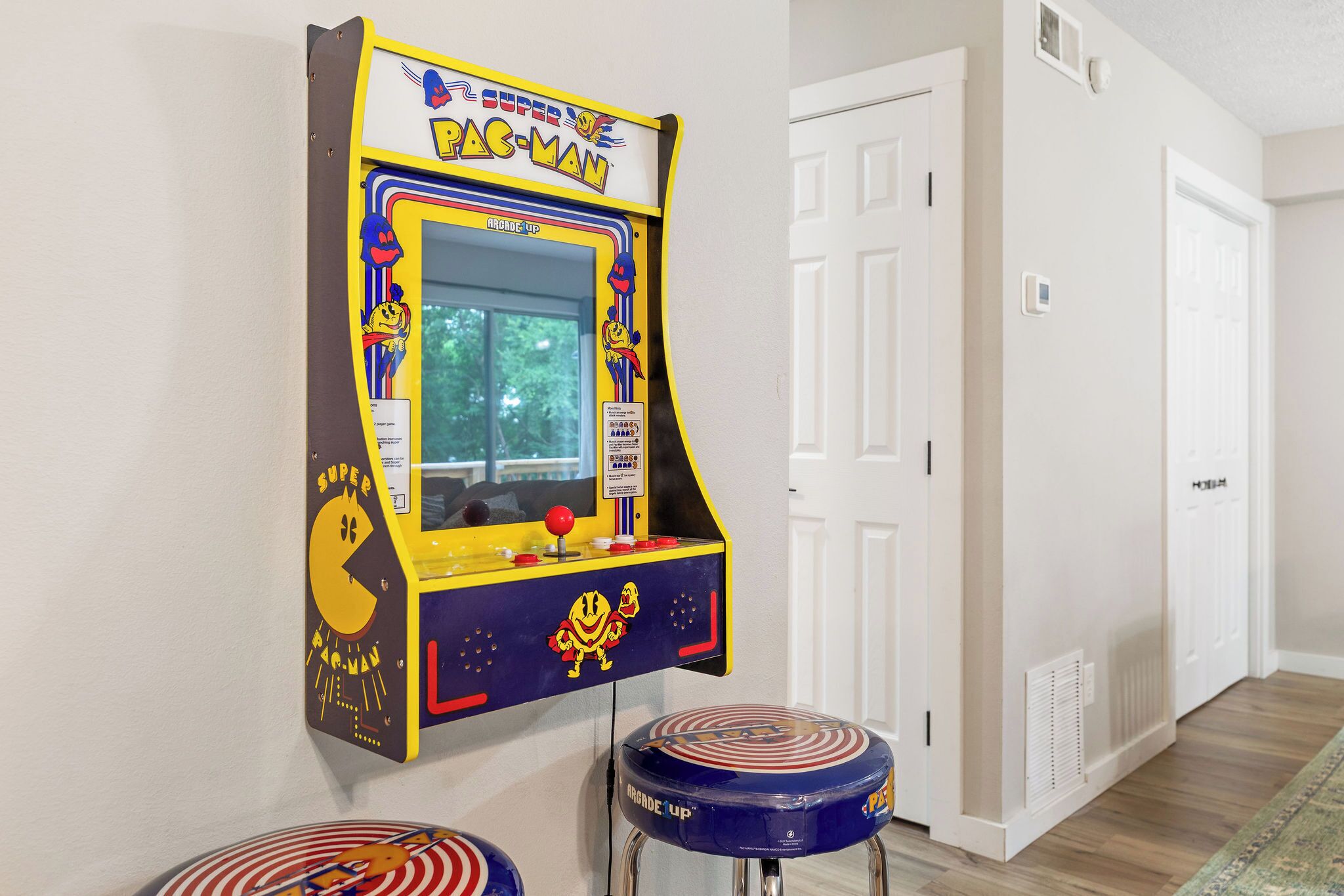 Ein Pac-Man-Spielgerät, eine Tür und ein Sitzhocker mit Muster.