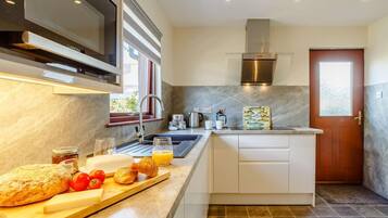 A modern kitchen with a built-in oven, stainless steel range hood, and a window.