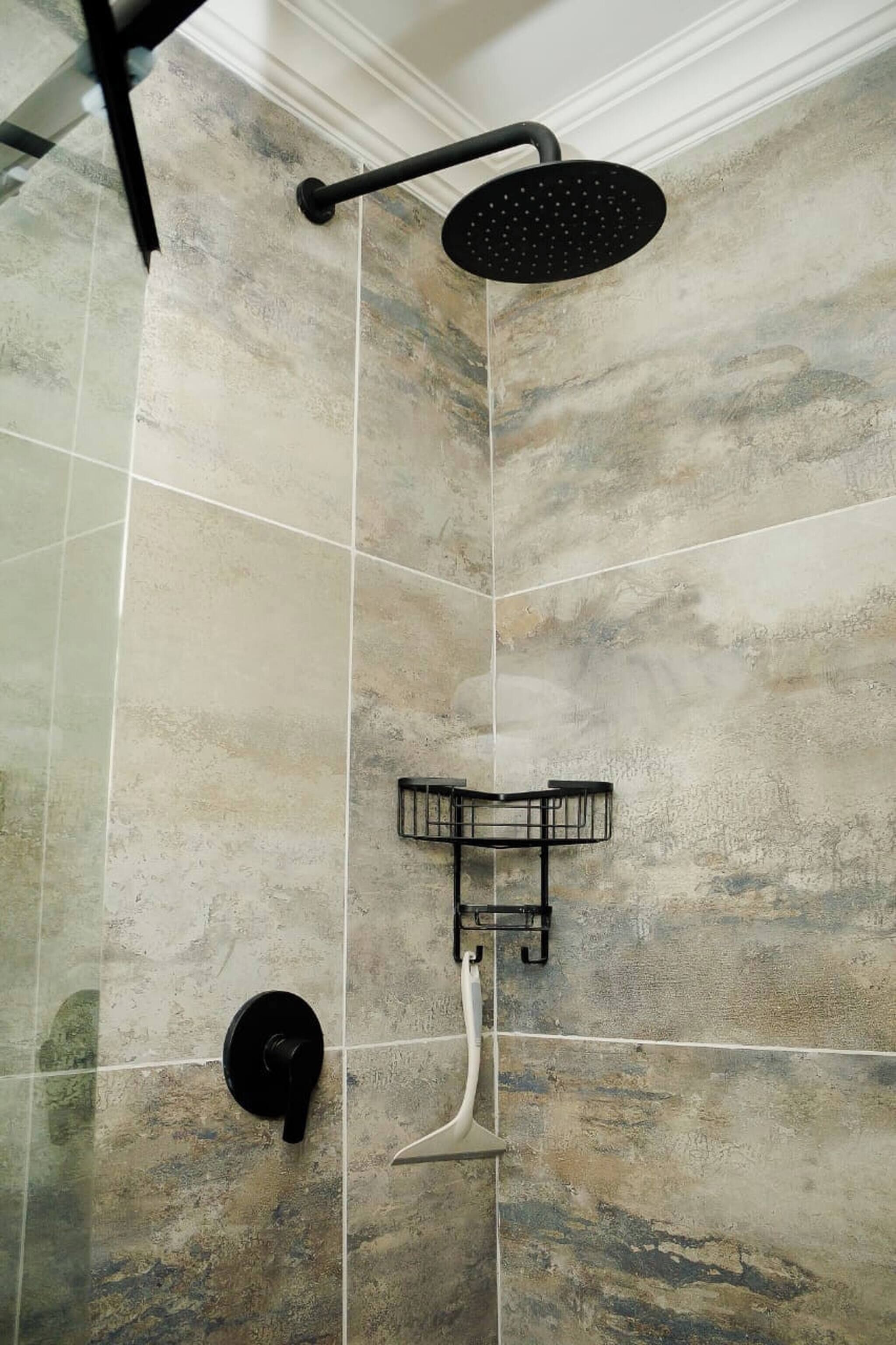 A shower area with a rain showerhead, a handheld showerhead, and a wall-mounted towel rack.