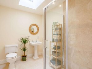 Een badkamer met toilet, wastafel en een douchecabine van glas.