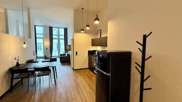 Eine moderne Küche mit einem schwarzen Kühlschrank, Holzböden und Pendelleuchten.
