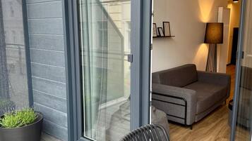 Ein modernes Wohnzimmer mit Sofa, einem Sessel, einem Blumentopf und einer Glastür zum Außenbereich.