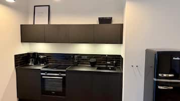 Eine moderne Küche mit dunklen Schränken, einem Backofen, einer Spüle und einem Kühlschrank.
