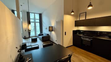Eine moderne Küche mit dunklen Schränken, einem Esstisch und einer Sitzecke mit einer Couch und Sesseln.