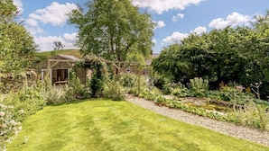 A garden with a lawn, a wooden fence, and a building with a sloped roof. - 1 Bed in Matlock (oc-89283) (Stanton Lees)