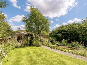 Ein Garten mit Rasen, einem Holzzaun und einem Gebäude mit Schrägdach.
