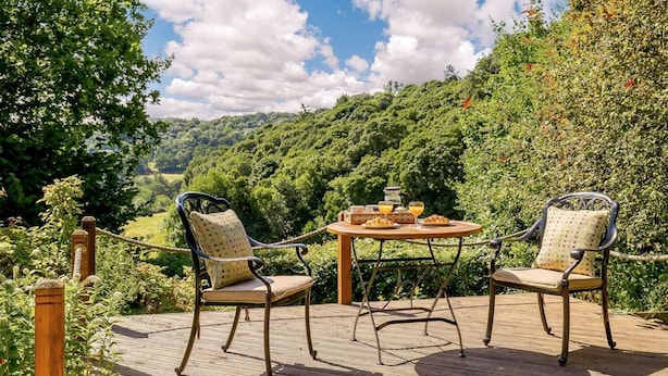A wooden deck with two chairs and a table set for breakfast, overlooking a lush green valley. - 1 Bed in Matlock (oc-89283) (Stanton Lees)