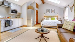 A cozy loft-style room with a kitchenette, a bed with a headboard, and a round coffee table. - 1 Bed in Matlock (oc-89283) (Stanton Lees)