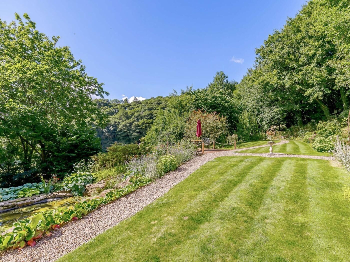 A well-maintained garden with a lawn, a small pond, and a variety of plants.