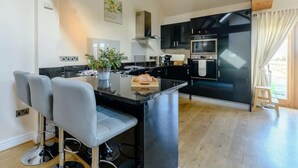 Una cocina moderna con gabinetes negros, una isla central y un área de comedor con dos sillas.