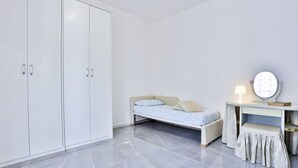 Une chambre à coucher avec un lit, une coiffeuse avec un miroir et une armoire.