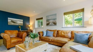 Ein Wohnzimmer mit einem braunen Ledersofa, einem Holztisch und einem weißen Teppich.