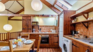 Une cuisine rustique avec des meubles en bois, une table à manger avec des chaises, un lave-linge et un four à micro-ondes.