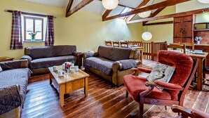 Un intérieur rustique avec des poutres apparentes, un coin repas et un espace salon.